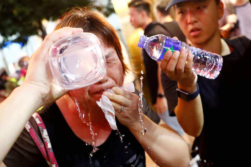 Женщина промывает глаза после применения полицией Гонконга слезоточивого газа