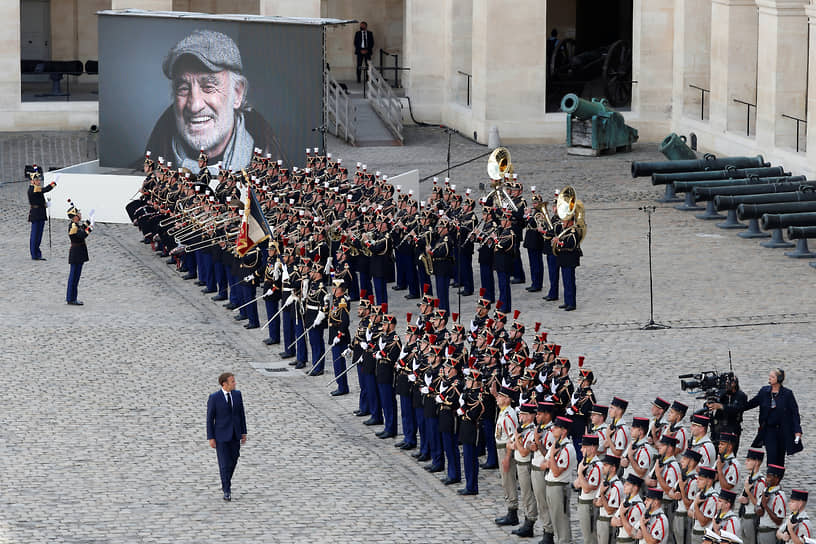 В Почетном дворе исторического Дома Инвалидов был установлен большой портрет улыбающегося актера 
&lt;br>На фото: президент Франции Эмманюэль Макрон (перед оркестром)