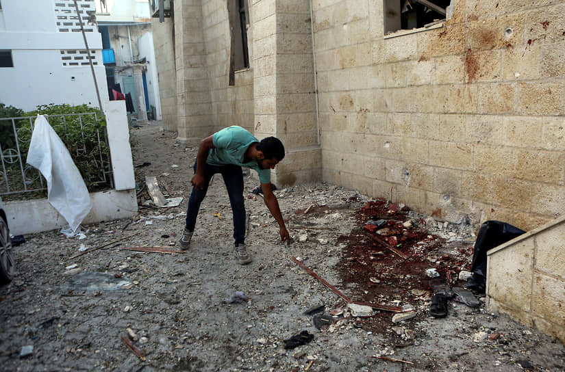 Палестинец осматривает повреждения в больнице Аль-Ахли
