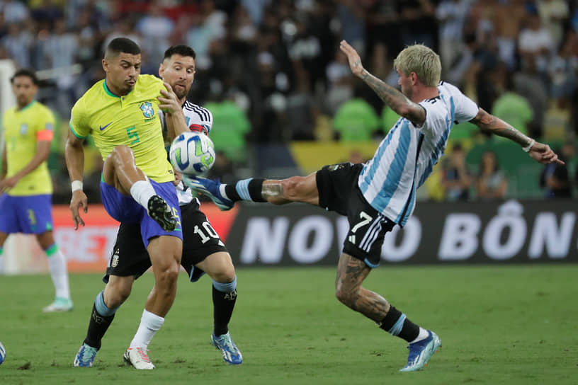 Бразильский полузащитник Андре (слева) в столкновении с аргентинскими игроками — нападающим Лионелем Месси и полузащинтником Родриго Де Паулем 
