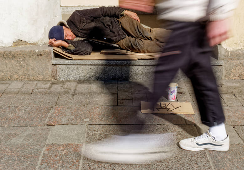 Бездомный мужчина спит на тротуаре