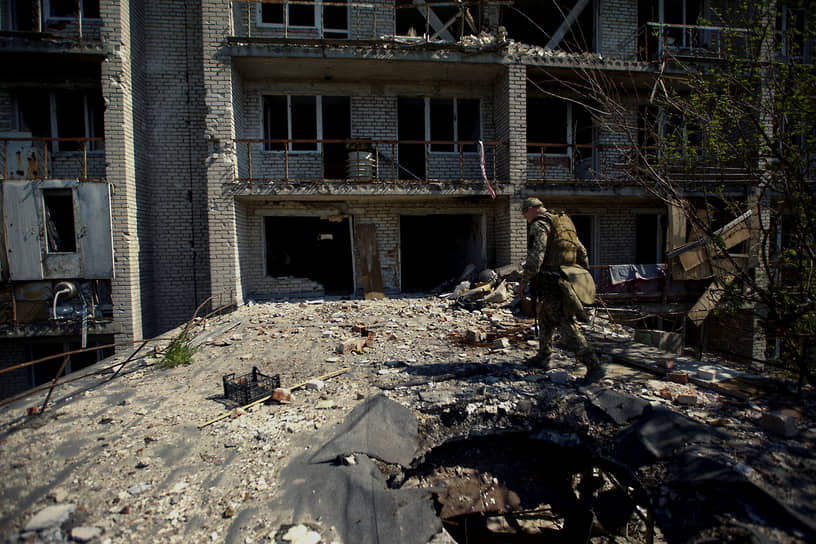 Военный рядом с разрушенным домом в Марьинке