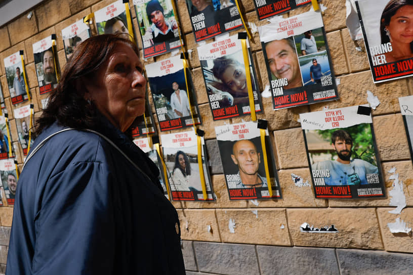 Женщина у стенда с фотографиями удерживаемых в заложниках «Хамасом»