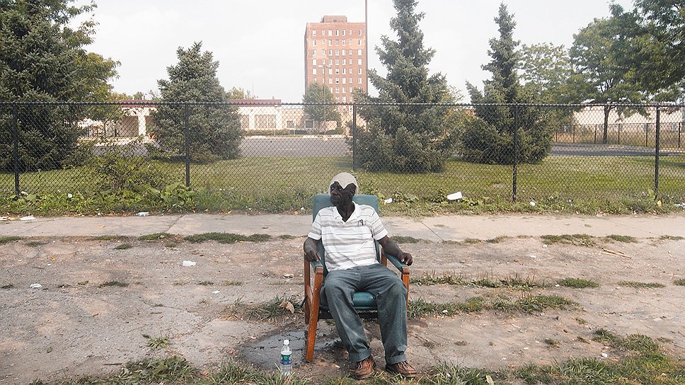 Бездомный ожидает обед возле благотворительного центра