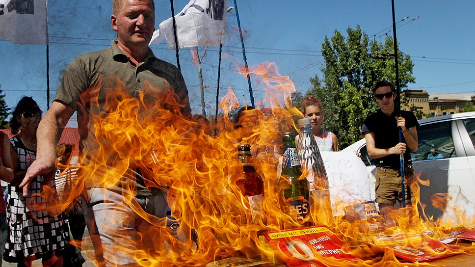 Участники акции протеста против блокирования импорта украинских товаров в Россию сжигают российские продукты перед посольством России в Киеве