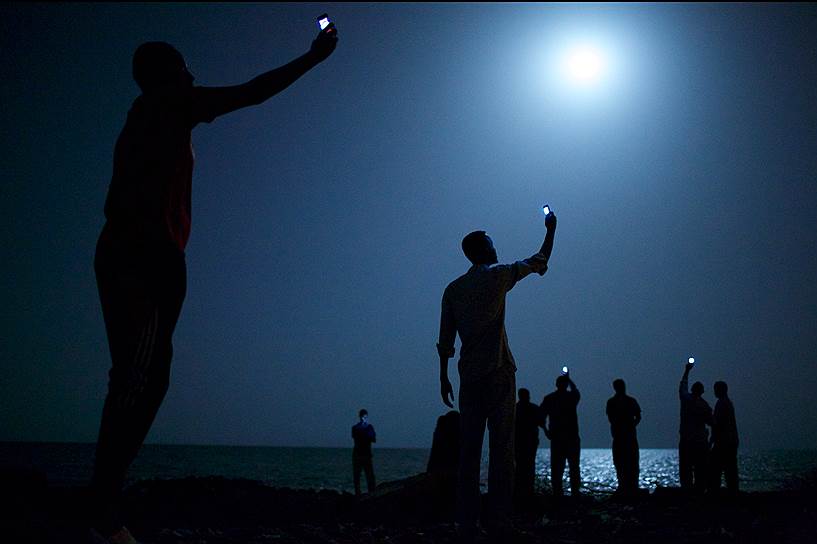 Фотография года по версии World Press Photo. Джон Стенмайер, США, для National Geographic. Африканские мигранты в Джибути пытаются поймать дешевый сигнал из Сомали 
