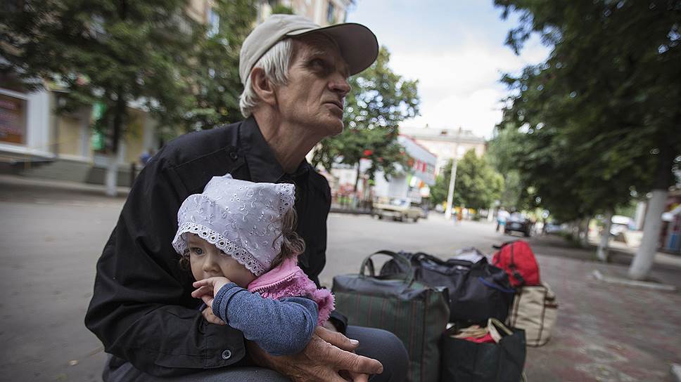 68-летний Виктор со своей 11-месячной внучкой Алисой ждут автобуса, который увезет их из воюющего Славянска на восток 