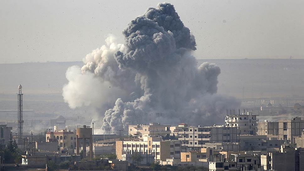 Сражение за Кобани (на фото — дым, поднимающийся над этим городом) видно даже отсюда, с турецко-сирийской границы, где сейчас находятся многие беженцы из числа курдов 
