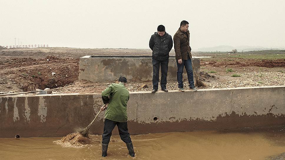 Работники компании-застройщика в Чанша убирают грязь после ночного дождя, чтобы на стройку смогли проехать грузовики 
