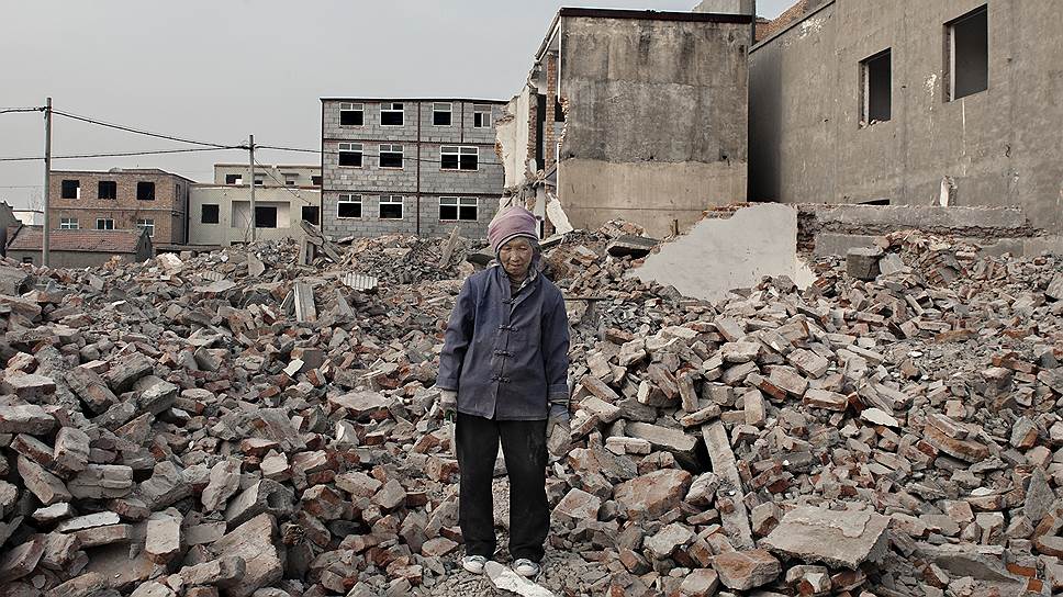 Женщина собирает уцелевшие кирпичи на месте снесенного квартала в Чжэнчжоу. Она продаст их строительной компании