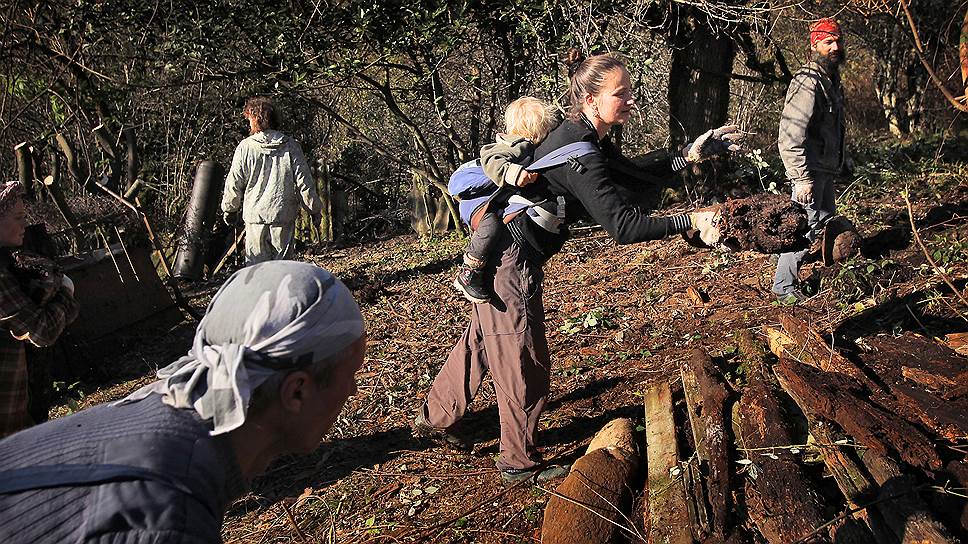 Виктория с ребенком за спиной помогает расчищать сад своим новым соседям — Сергею и Ольге 