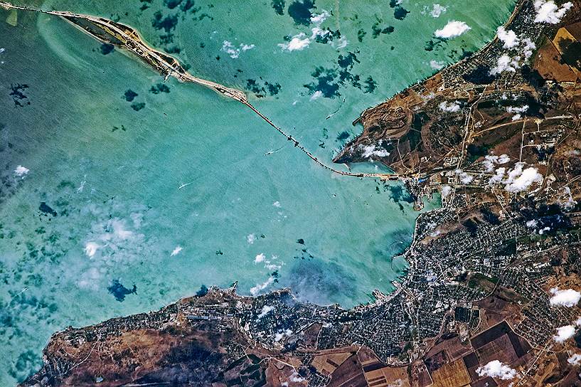 За строительством моста через Керченский пролив космонавты уже традиционно следят с борта МКС. Снимок сделан в августе 2017 года, сразу после установки одной из самых сложных конструкций. Железнодорожную арку весом 6 тысяч тонн подняли на фарватерные опоры на высоте 35 метров над уровнем моря. На фотографии как раз ее отчетливо видно  

