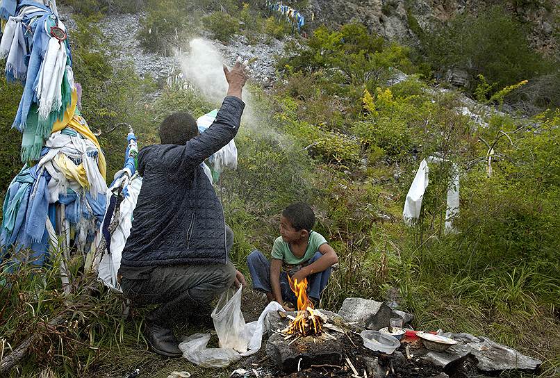 Эртине Бандан с сыном Бимдорчем совершают ритуальное действие (развеивание муки) у священного источника в долине реки Качык (юго-восток Тувы) 
