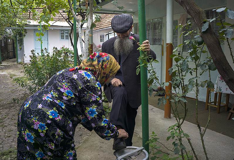 Пожилая пара из Ивановки. Жена помогает мужу завязать шнурки. Сам он с этим не справляется из-за проблем со здоровьем 