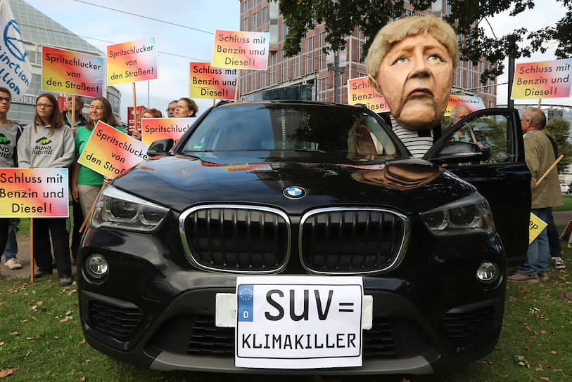 Один из протестующих экоактивистов в маске канцлера Ангелы Меркель