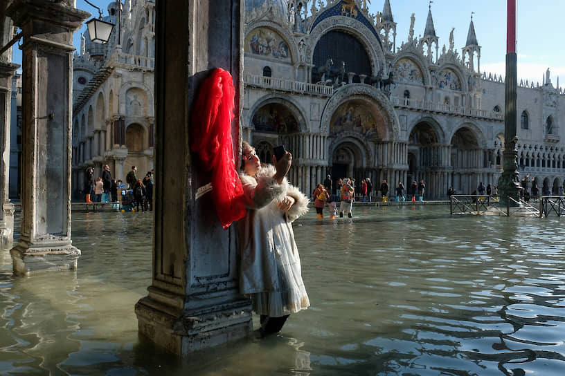 Туристка фотографируется на площади Святого Марка во время сезонного наводнения в Венеции