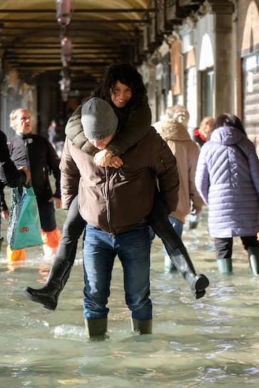 Люди, гуляющие по затопленной площади Святого Марка