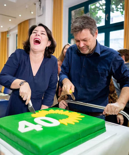 Претенденты на пост канцлера ФРГ от Партии зеленых Роберт Хабек и Анналена Бербок режут торт, испеченный в честь 40-летия своего партии