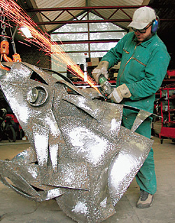 Дмитрий работает над скульптурой из металла «Очень дикий лосось»