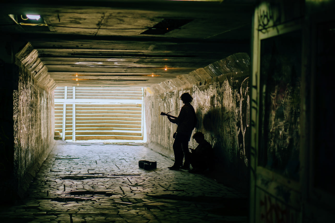 Уличный музыкант играет на гитаре в подземном переходе на перекрестке улиц Горького и Советской