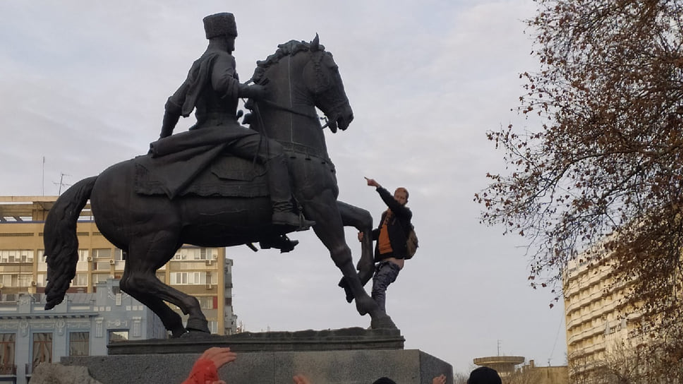 Мужчина забрался на памятник возле здания администрации края