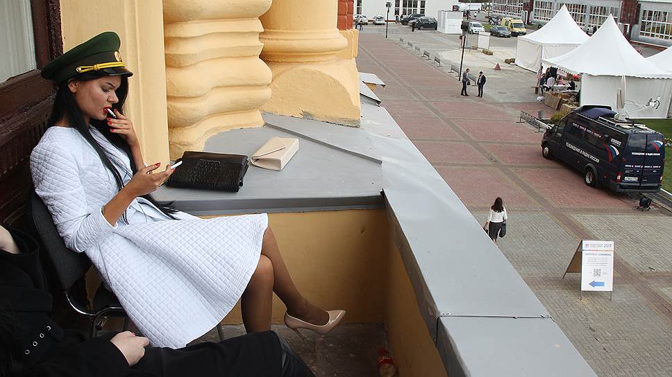 Девушка в фуражке от униформы курит на балконе Нижегородской ярмарки