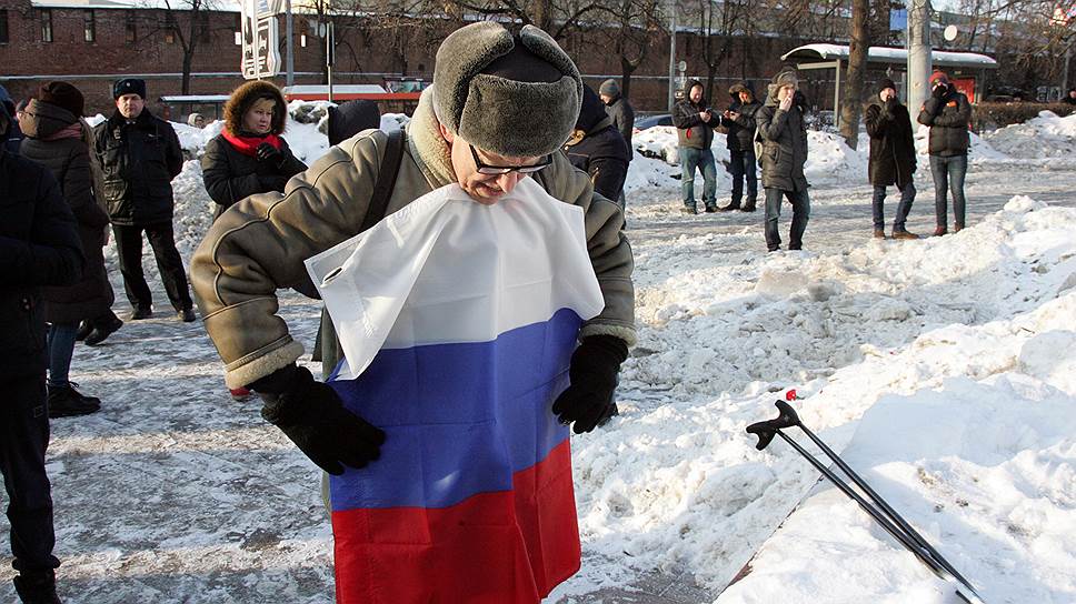 Участник митинга памяти Немцова сворачивает российский триколор. Февраль 2018 года