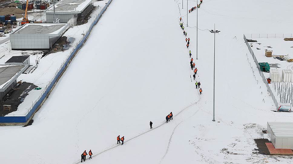 Рабочие идут на обед мимо строящегося футбольного стадиона. Март 2018 года