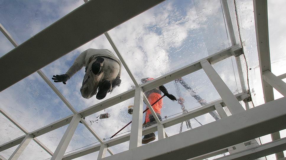 Рабочий во время монтажных работ на стеклянной крыше нового пешеходного перехода около футбольного стадиона. Июнь 2018 года