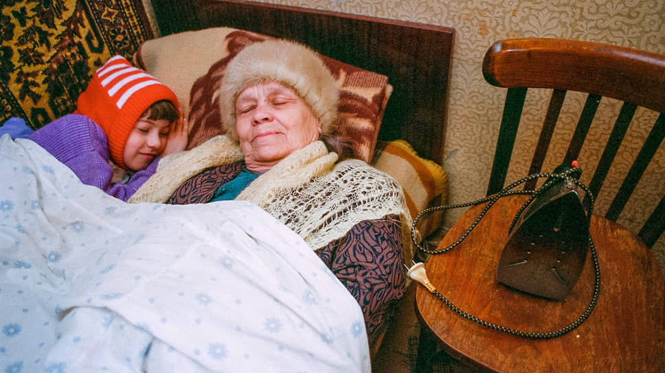 Даже в холоде людям хочется спать. Бабушка и внучка греются утюгом в квартире дома на проспекте Ленина, куда в октябре 1999 года не успели подать отопление