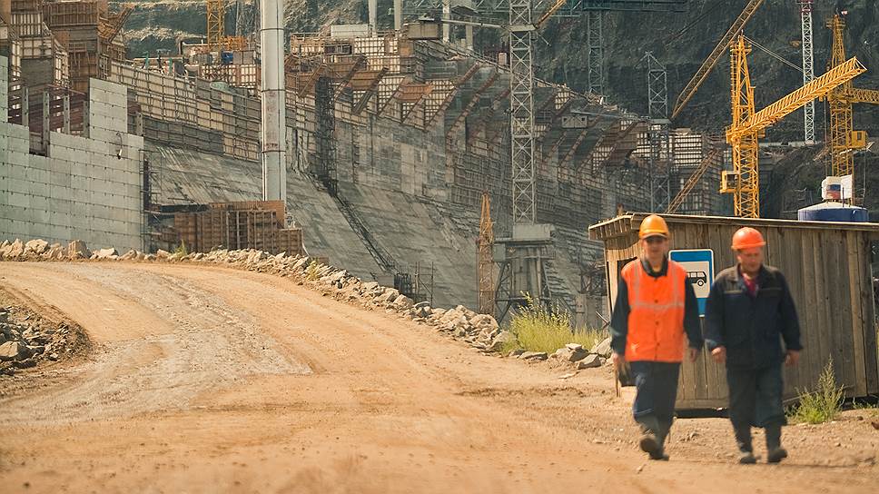 Рабочие идут по технологической дороге, соединяющей берега Ангары у каменно-набросной части плотины.