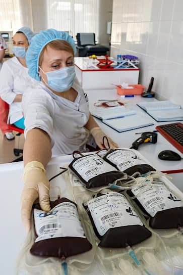 Сотрудники лаборатории Новосибирского клинического центра крови (ГБУЗ НСО НКЦК) с медицинскими мешками с кровью