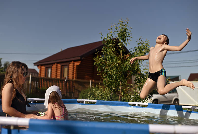 Дети купаются в бассейне на даче в селе в Омске во время режима самоизоляции