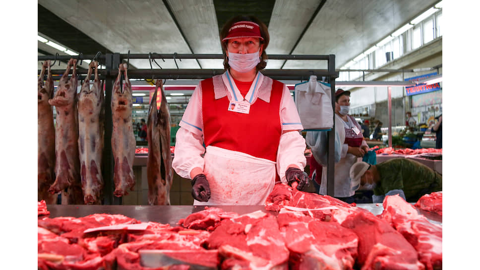 Продавщица мяса в медицинской маске за прилавком на Октябрьском рынке