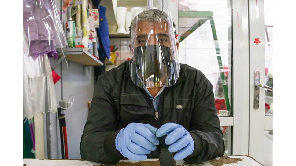 Мужчина в маске, перчатках и защитном экране для лица на открывшемся после пандемии Центральном рынке в Новосибирске