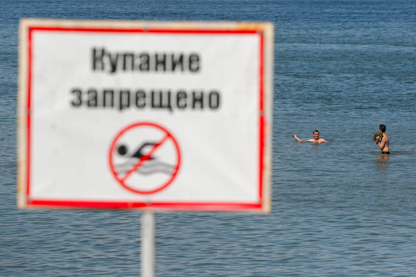 Отдыхающие купаются в Обском море на фоне таблички «Купание запрещено» на берегу пляжа «Бугринская роща» в Новосибирске