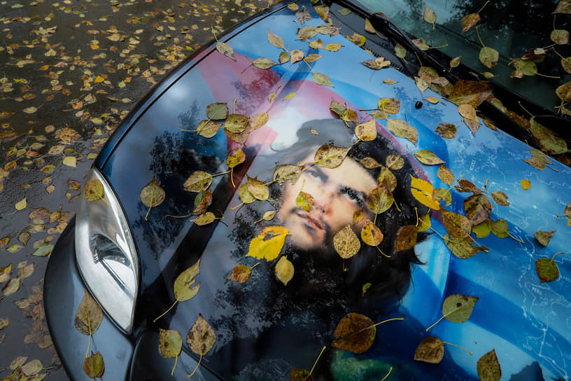 Портрет латиноамериканского революционера, команданте Кубинской революции Эрнесто Че Гевары на капоте автомобиля в осенней золотой листве в одном из дворов Новосибирска