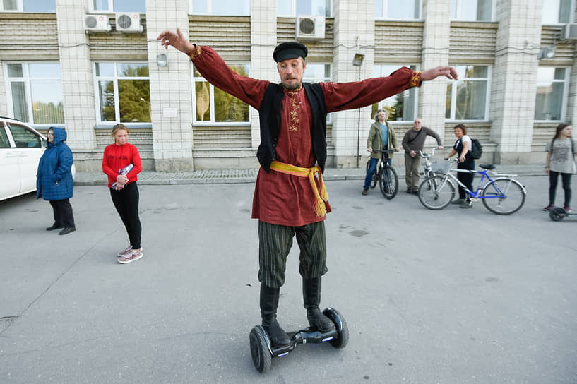 Участник этнокультурного фестиваля в народном костюме катается на гироскутере в новосибирском Академгородке