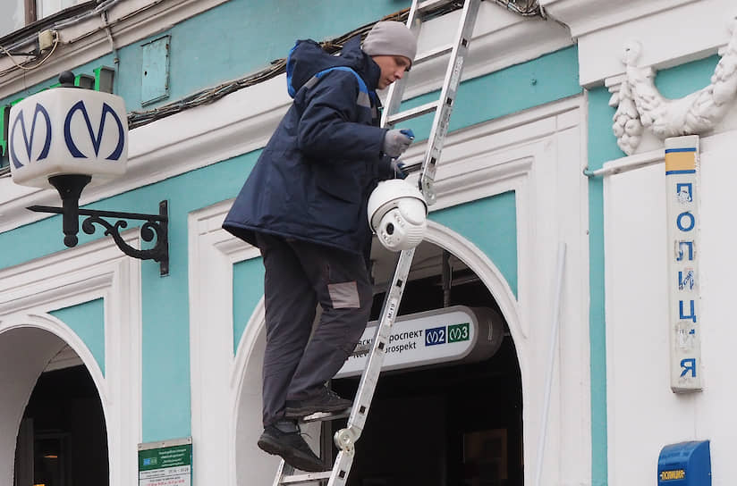 Специалист по установке приборов уличного видеонаблюдения перед монтажом камеры на доме в центре Санкт-Петербурга
