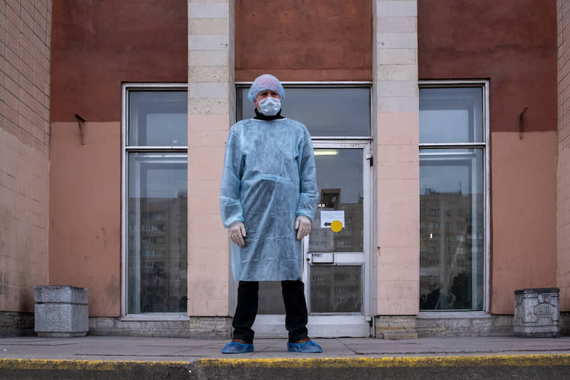 Мужчина в защитной спецодежде на крыльце здания учебно-клинического комплекса №2, находившегося на карантине в рамках мер нераспространения коронавируса 2019-NCOV