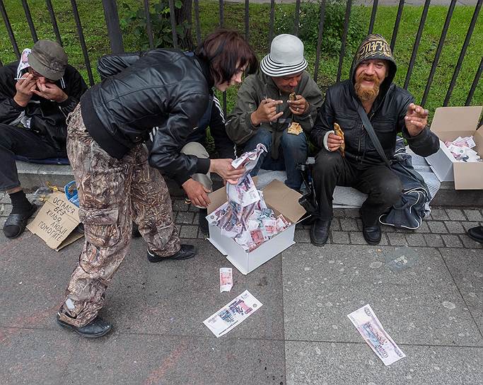 Бездомные с коробкой наполненной бумажками в виде денежных знаков Российской федерации 