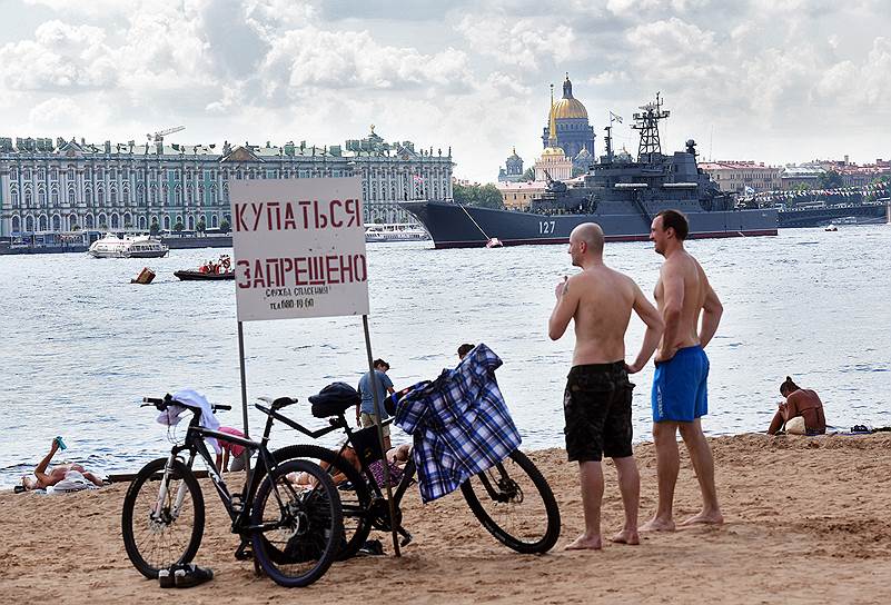 Отдыхающие на пляже Петропавловской крепости на фоне боевых кораблей в акватории Невы
