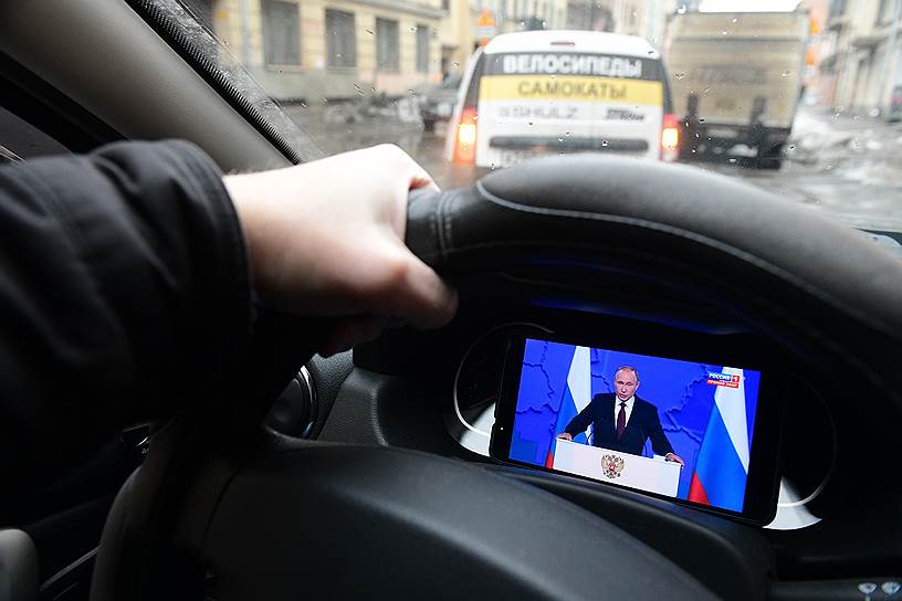 Водитель смотрит ежегодное Послание президента России Владимира Путина Федеральному Собранию в автомобиле на планшете