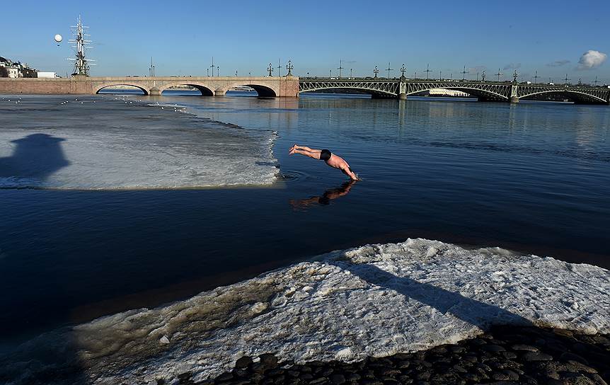 Участник клуба зимнего плавания &quot;Большая Нева&quot; у Петропавловской крепости ныряет в Неву на фоне Троицкого моста