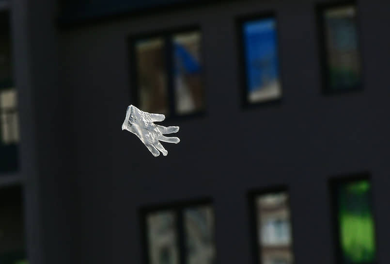 Использованная гигиеническая перчатка летит на фоне жилых домов 