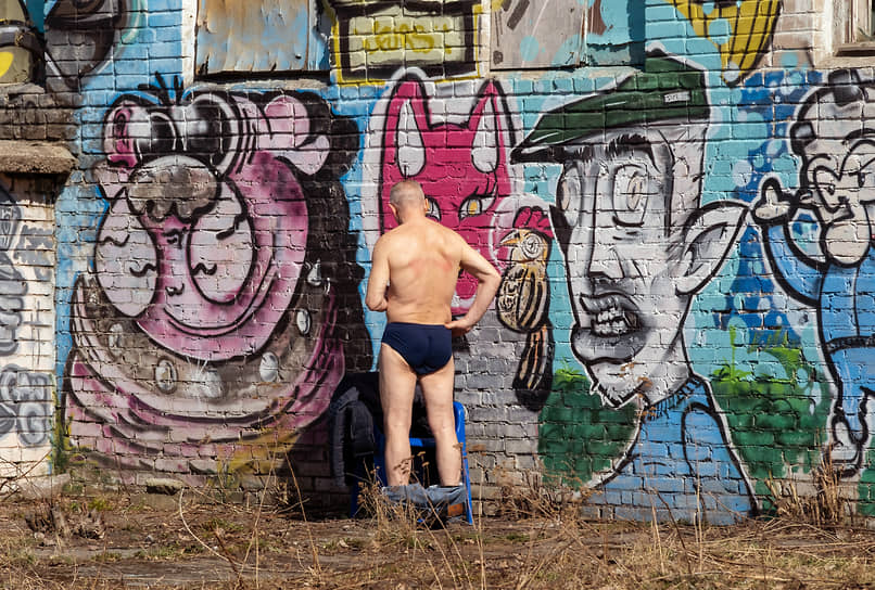 Мужчина загорает на фоне стены с граффити