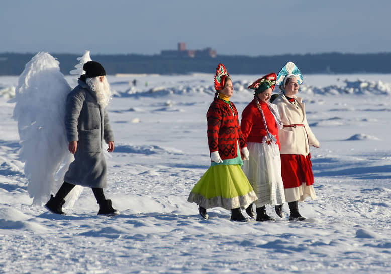 Женщины в кокошниках и мужчина в костюме Ангела прогуливаются по берегу Финского залива в районе Репино