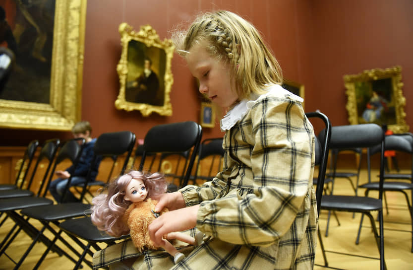 Девочка играет с куклой в академическом зале №14 перед концертом