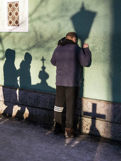 Мужчина у стены часовни Ксении Блаженной на смоленском кладбище