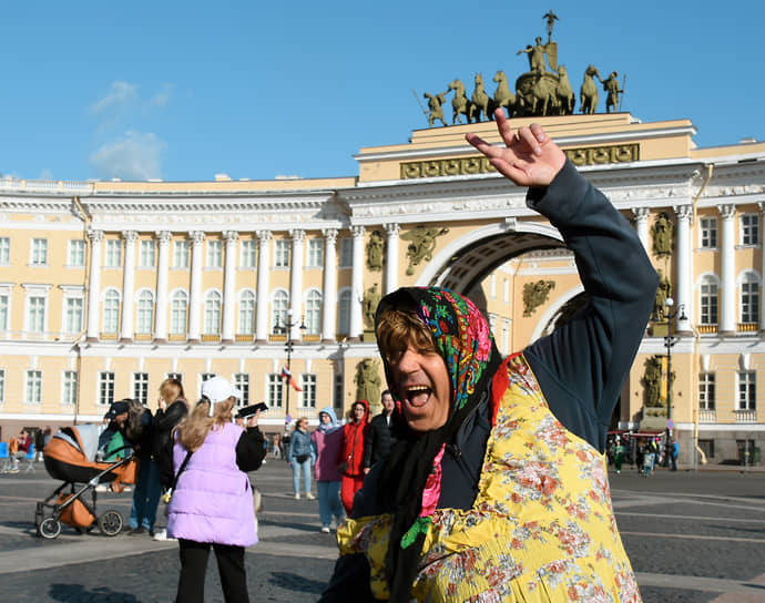 Празднование 320 -летия со дня основания Санкт-Петербурга. Жанровая фотография. Мужчина в женском платье, в платке танцует на Дворцовой площади